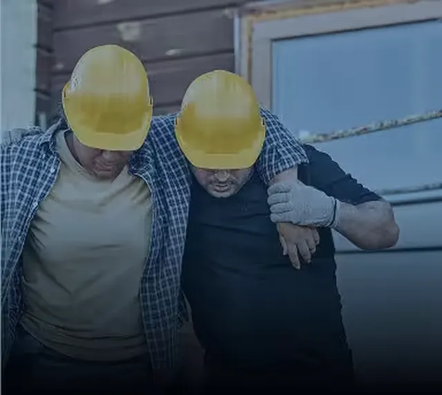 Two construction workers in hard hats, one helping the other
